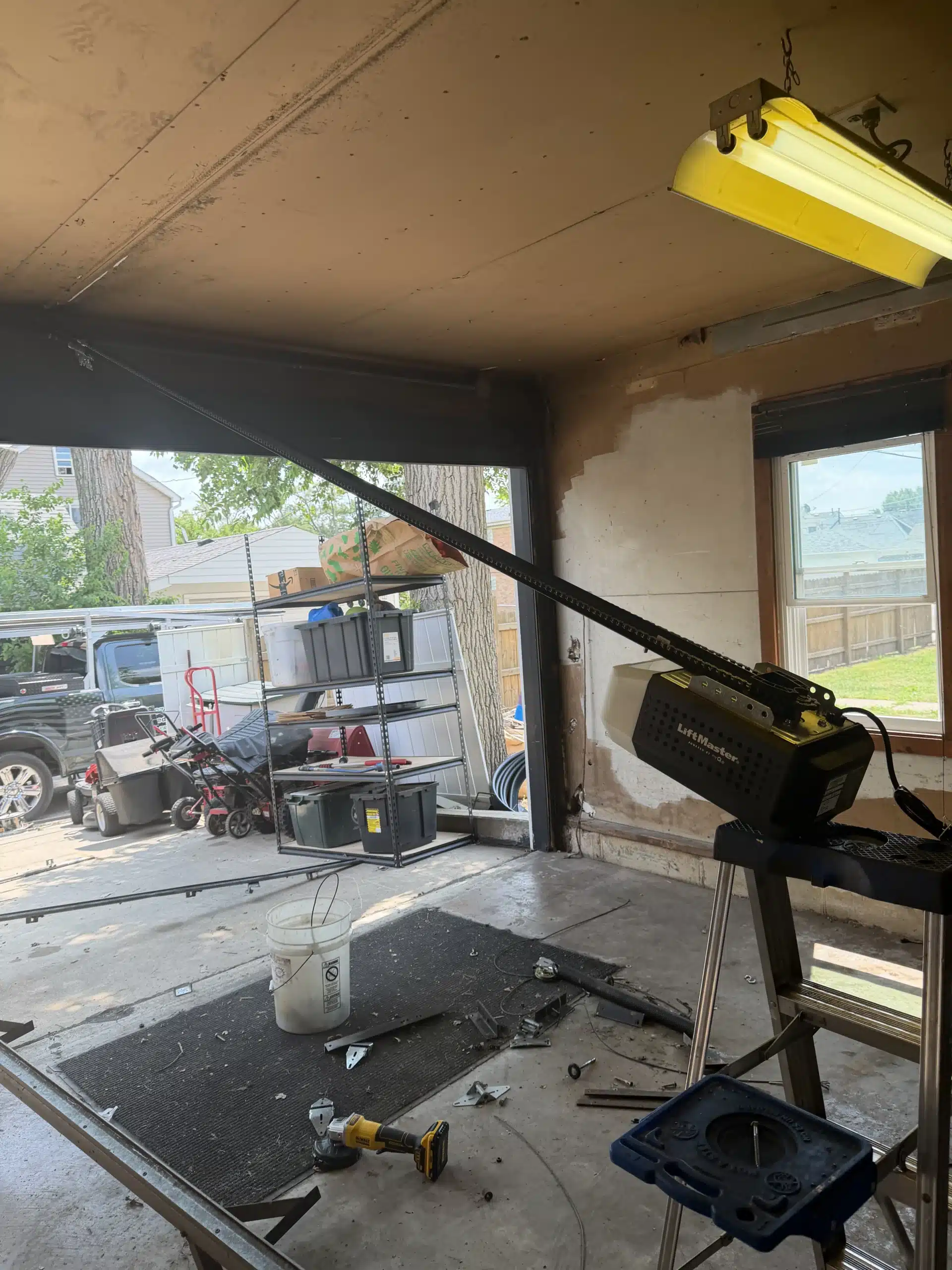 Interior view of a garage showing an automated garage door opener rail angled across the ceiling and workspace.